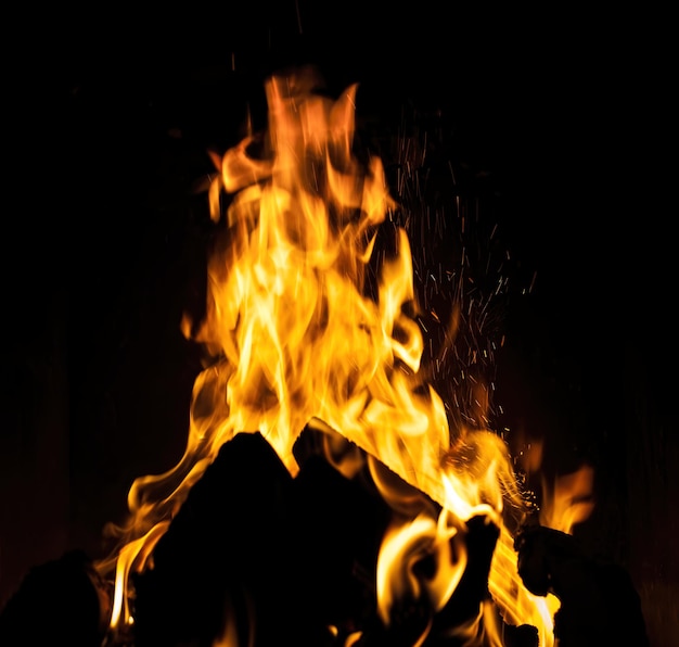 Flames, fire background and texture. Fireplace with wood and fire on a dark background