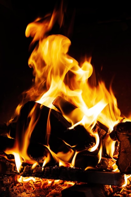 Flames, fire background and texture. Fireplace with wood and fire on a dark background