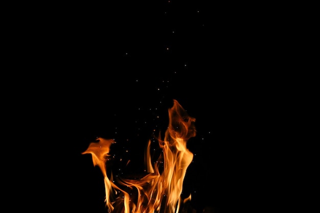 Foto fiamme di fuoco da un falò con molte scintille su sfondo nero