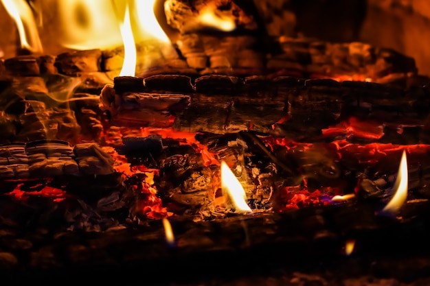 Flames of fire and hot coals of burned wood in the fireplace