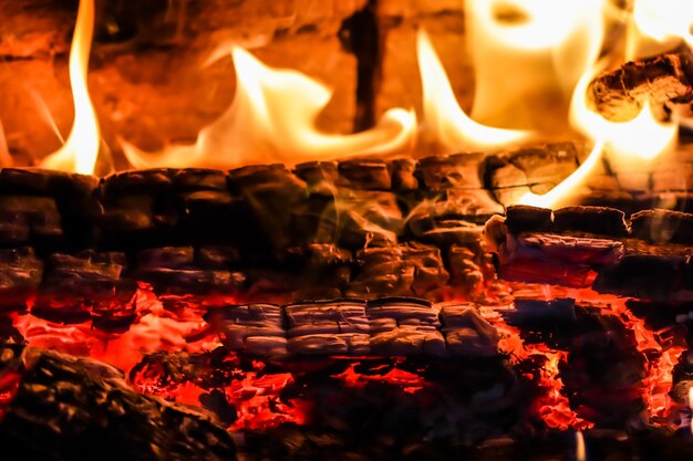 Flames of fire and hot coals of burned wood in the fireplace