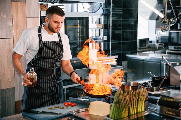 flames on the frying pan chef is on the kitchen preparing food