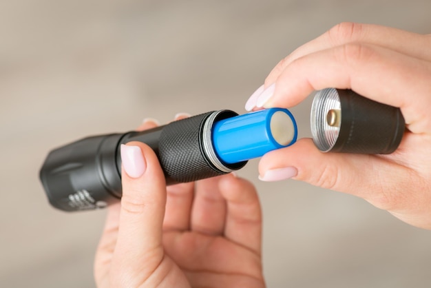 Flashlight with 18650 battery in female hands close up