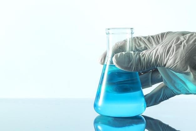 Flask in scientist hand with test tubes in rack background