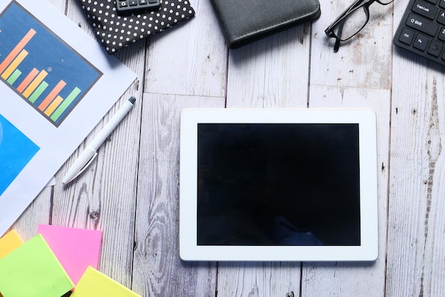 Flat composition of digital tablet and office stationary on black background