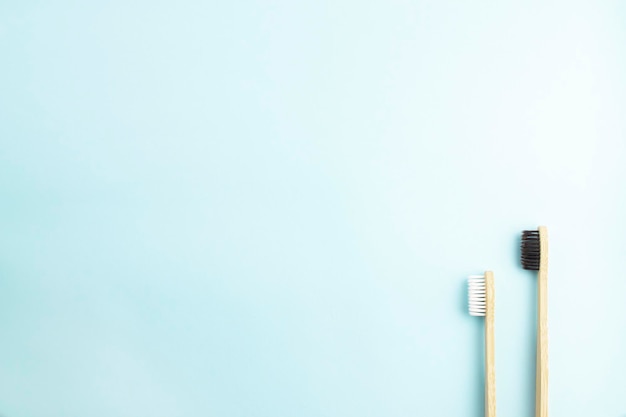 Flat composition with bamboo toothbrushes on blue banner background with place for text