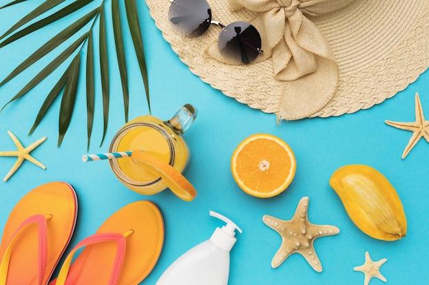 Flat composition with beach holiday accessories and fruits on blue background with copy space