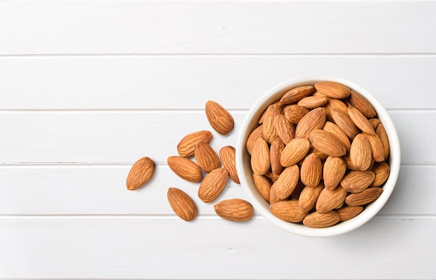 Flat lay of Almond nuts in white bowl on white wood