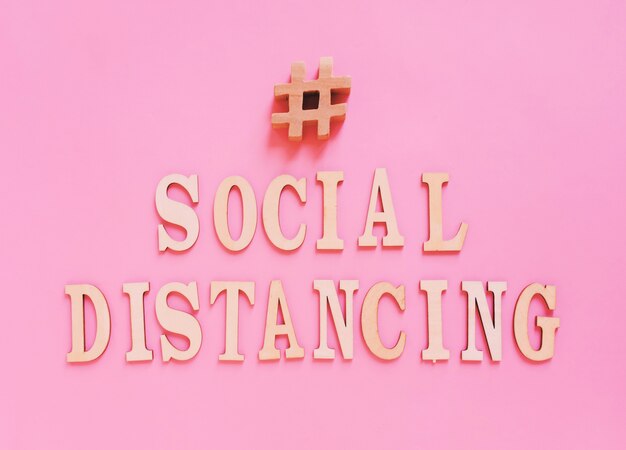 flat lay of alphabet wooden letter about hashtag social distancing concept on bright pink