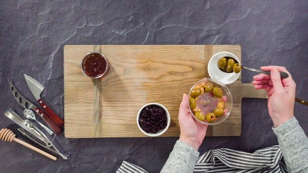 Flat lay. Arranging gourmet cheese, crakers, and fruits on a board for a large cheese board.