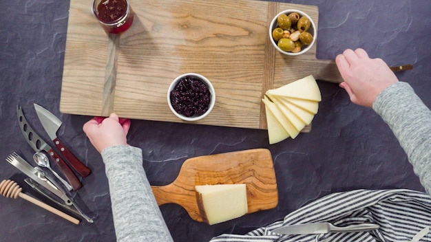 Flat lay. Arranging gourmet cheese, crakers, and fruits on a board for a large cheese board.