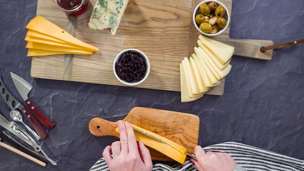 flat lay. arranging gourmet cheese, crakers, and fruits on a board for a large cheese board.