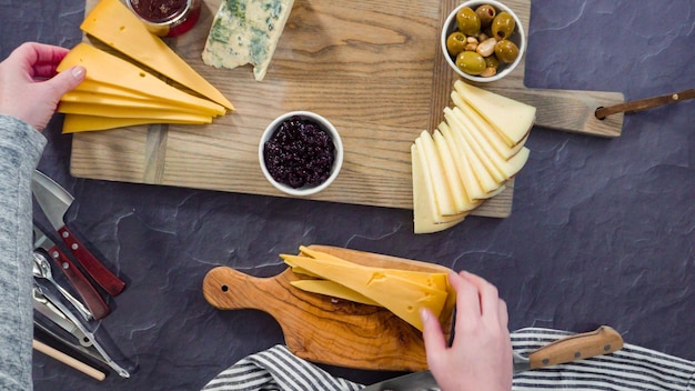 Flat lay. Arranging gourmet cheese, crakers, and fruits on a board for a large cheese board.