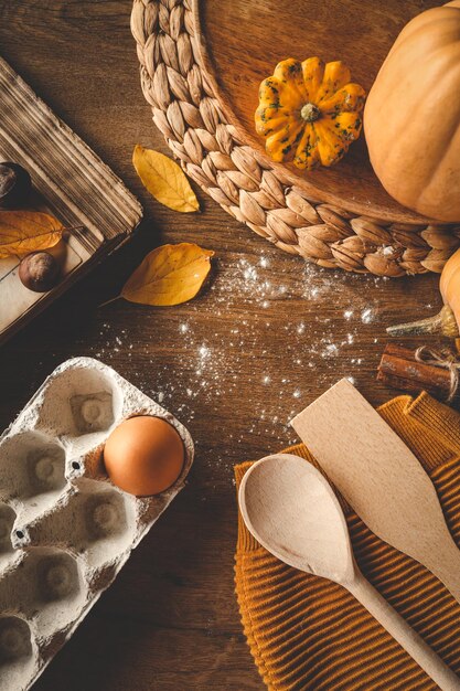 Flat lay autumn background for cooking Pumpkins cookbook kitchen utensils on a wooden table space for text