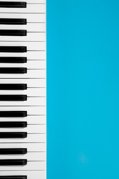 Flat lay background with piano white synthesizer on blue background musical keys isolated top view copy space