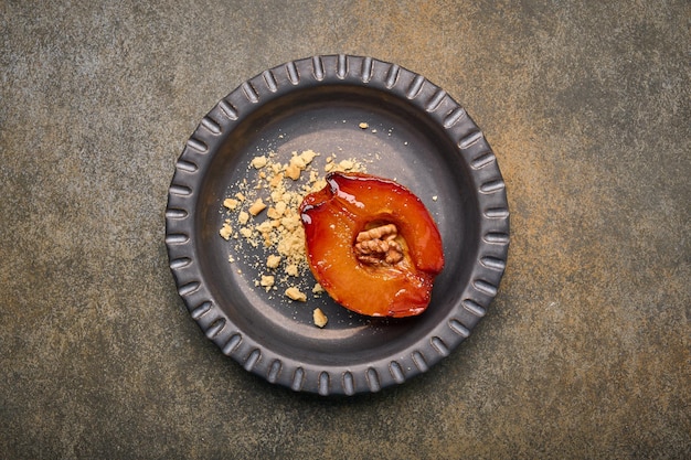 Flat lay baked quince with honey walnut and cinnamon on dark plate on rustic background top view