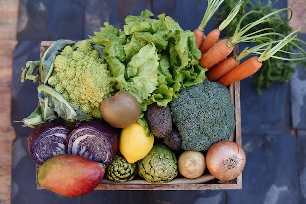 Flat lay of a basket of organic vegetables on a slate background