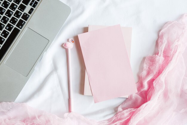 Flat lay bed workspace with laptop, notebook, pen