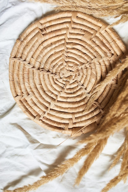 Photo flat lay of beige reeds pampas grass on the white textile linen tablecloth background, beautiful pattern with neutral colors, minimal, stylish, trend concept, top view