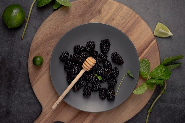 Photo flat lay of blackberries on plate with mint and limes