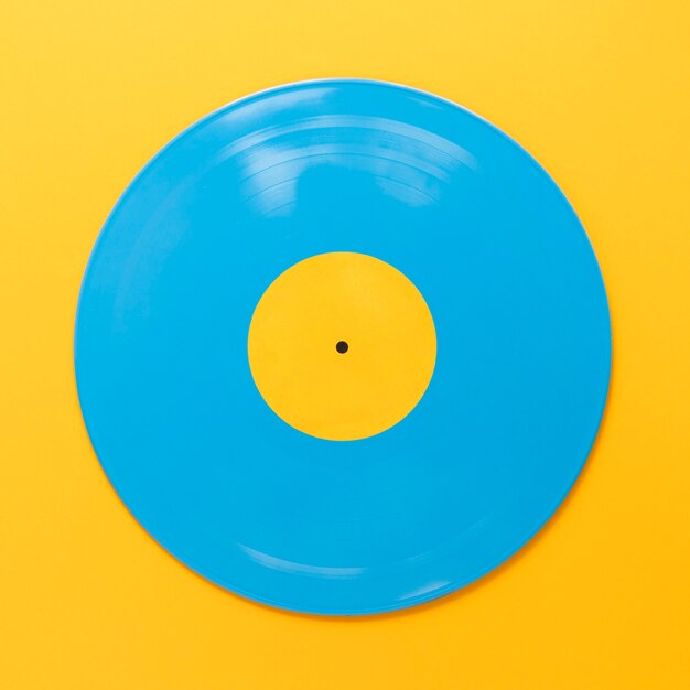 Disco vinile blu piatto disteso su sfondo giallo