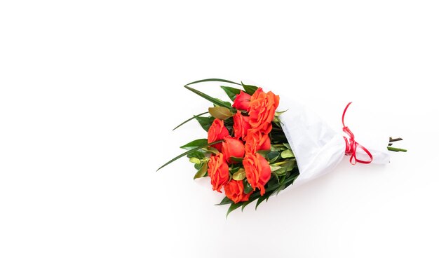 Flat lay. Bouquet of red roses and green leaves on a white background.