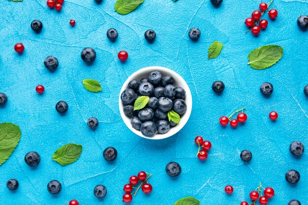 Photo flat-lay bowl and scattered berries with leaves