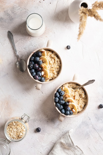 Flat lay of bowls with oatmeal porridge and blueberries