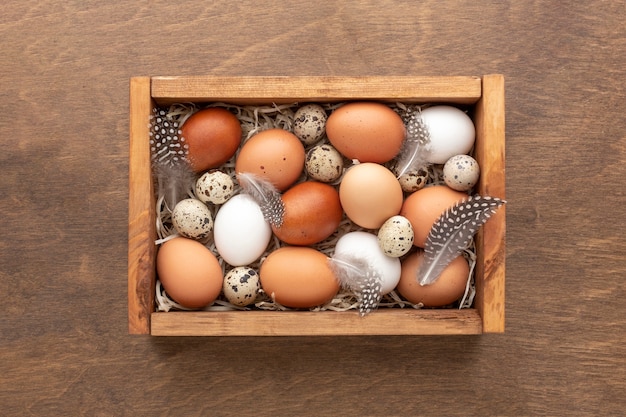 Flat lay of box with eggs for easter on wooden background