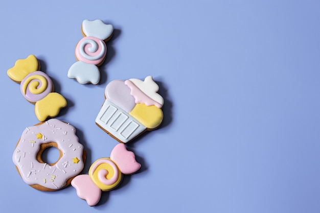 Flat lay of bright glazed gingerbread cookies on a blue background copy space.