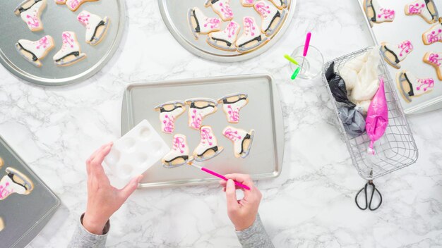 Photo flat lay. brushing edible glitter on iced figure skate sugar cookies.