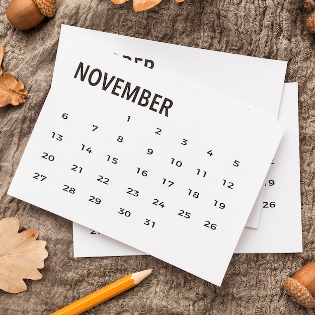 Flat lay of calendar with autumn leaves and acorns