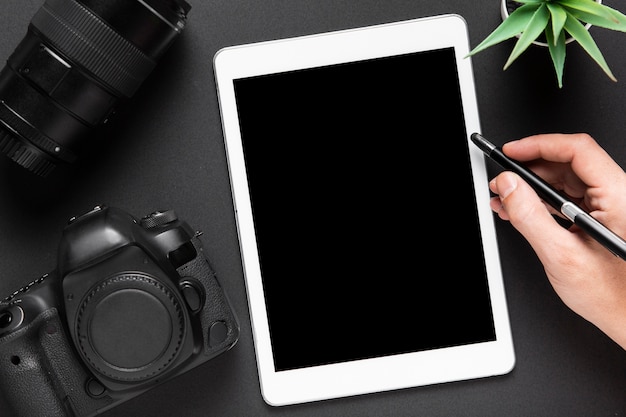 Flat lay of camera and tablet on black background