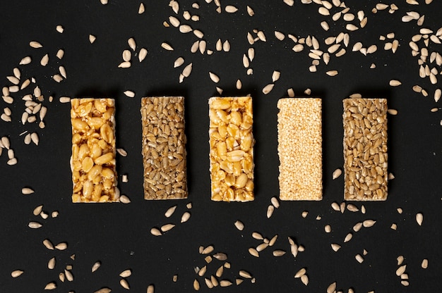 Assortimento di barre di cereali piatto laici con semi di girasole su sfondo chiaro