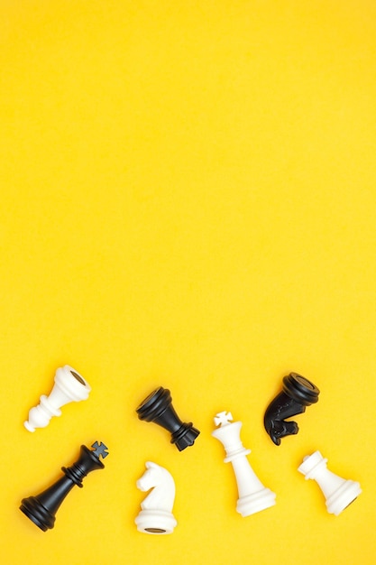 Flat lay of chess pieces on a yellow background, copy space. vertical photo