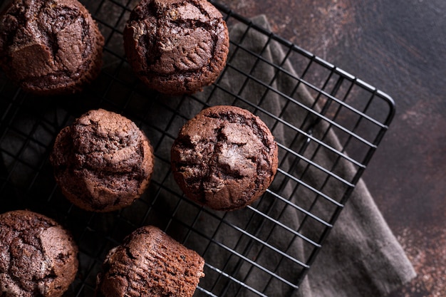 Foto disposizione piana dei muffin al cioccolato sulla griglia di raffreddamento con un panno