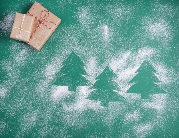 Flat lay christmas background with green tree, craft present  and snow. Top view