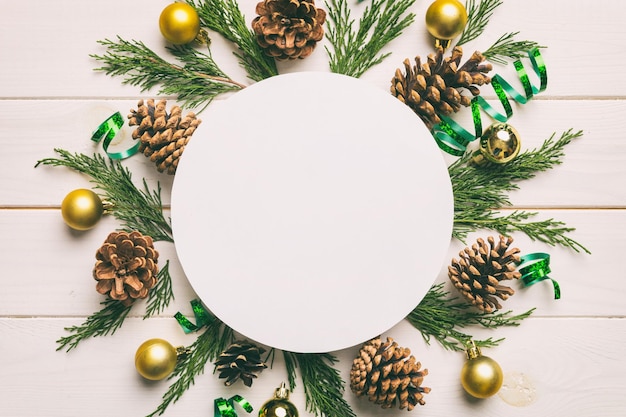 Flat lay Christmas composition Round Paper blank pine tree branches christmas decorations on Colored background Top view copy space for text