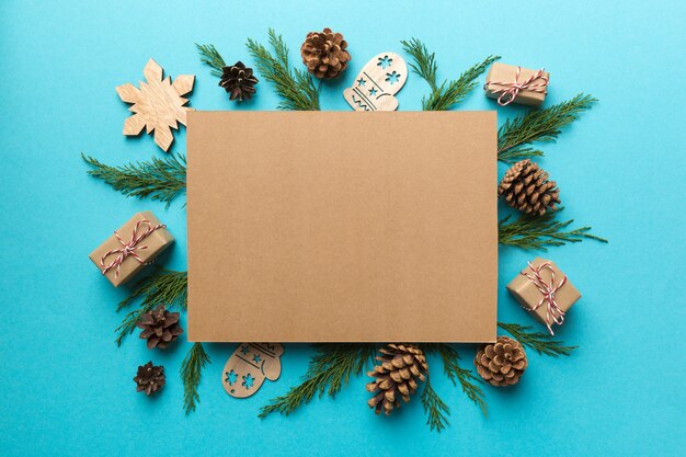 Flat lay Christmas composition. square Paper blank, pine tree branches, christmas decorations on Colored background. Top view, copy space for text.