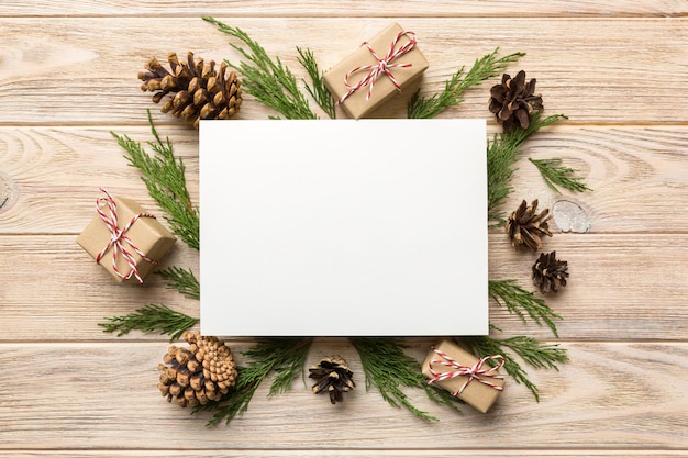 フラットレイクリスマス作曲。正方形の紙の空白、松の木の枝、色付きの背景にクリスマスの装飾。上面図、テキスト用のスペースをコピーします。