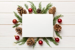 Flat lay christmas composition square paper blank pine tree branches christmas decorations on colored background top view copy space for text