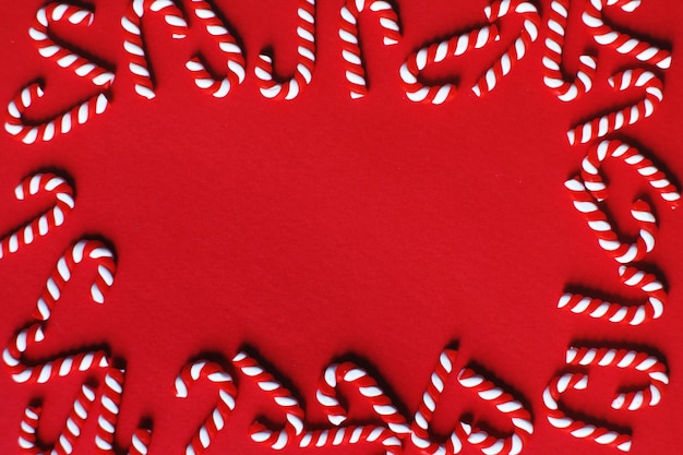 Photo flat lay christmas composition with frame of candy canes on a red background copy space for text