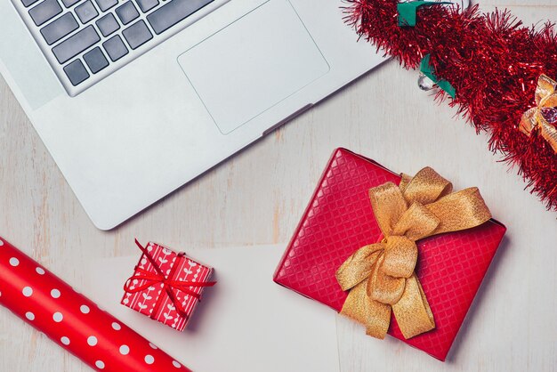 Disposizione piana del regalo di natale con il computer portatile sopra fondo di legno bianco