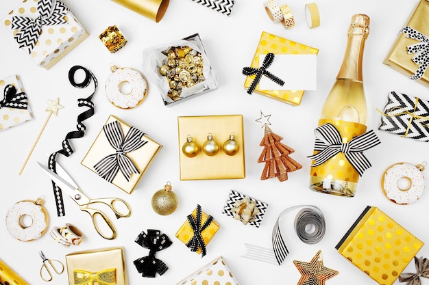 선물 상자, 샴페인 병, 활, 장식 및 포장지가 금색과 검정색으로 된 평평한 크리스마스 또는 파티 배경. 평평한 평지, 평면도