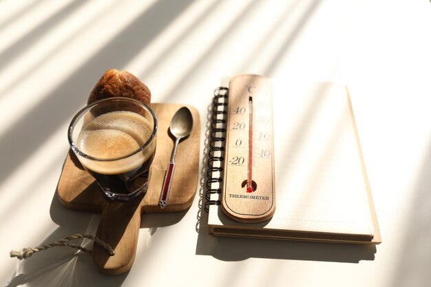 Flat lay Coffee and cup cake and notebook and thermometer with sunshine