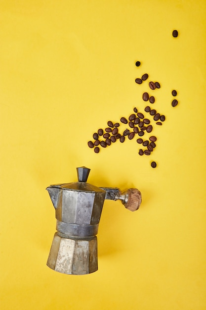 Flat lay of coffee maker and coffee beans on yellow background