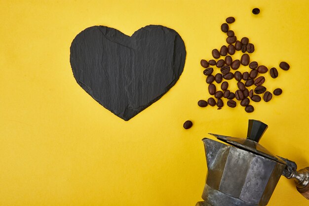 Flat lay of Coffee maker and coffee beans on yellow background.