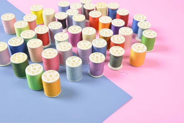Flat lay of colored thread rolls for sewing on two tone background.
