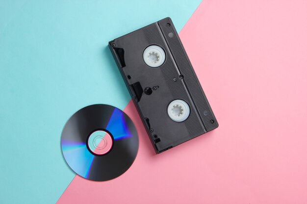 Flat lay composition of cd disc, audio cassette on pink blue.