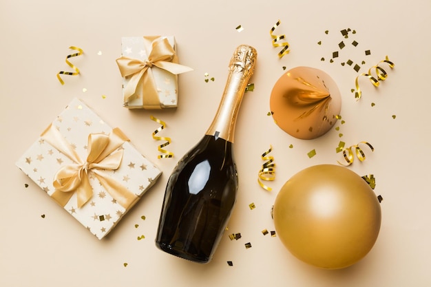 Flat lay composition of Champagne bottle gift box ribbons and confetti on colored background Flat lay top view holiday concept